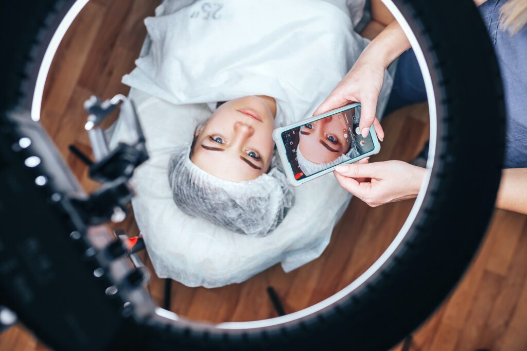 the beautician takes a photo of his work after the permanent makeup procedure